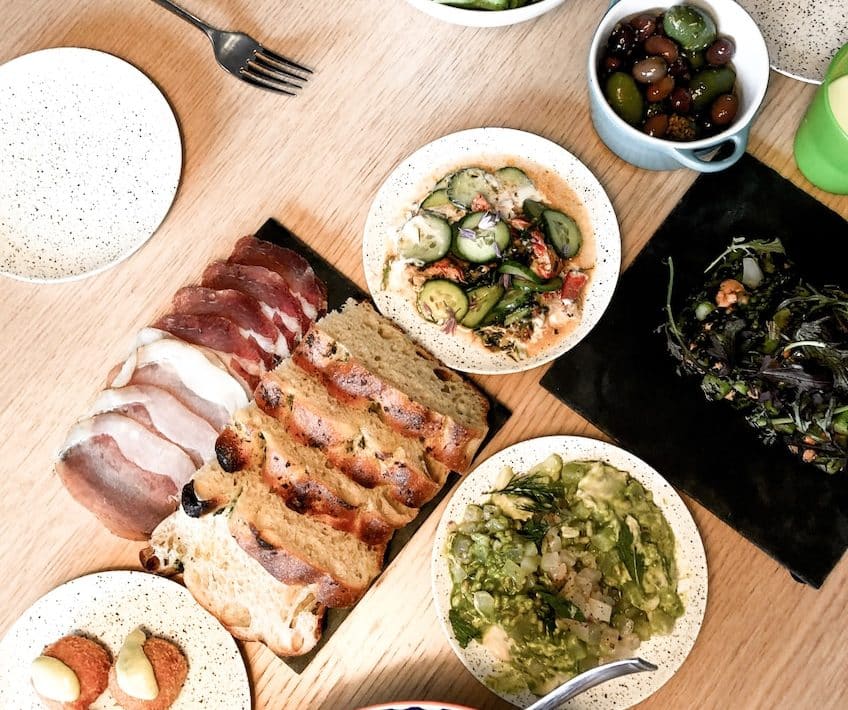 sliced meat on white ceramic plate beside green vegetable salad on white ceramic bowl